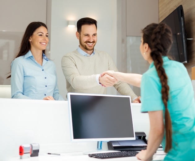 Oral surgery team member greeting patient at reception desk