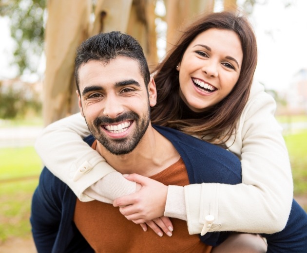 Man and woman smiling after full mouth restorations