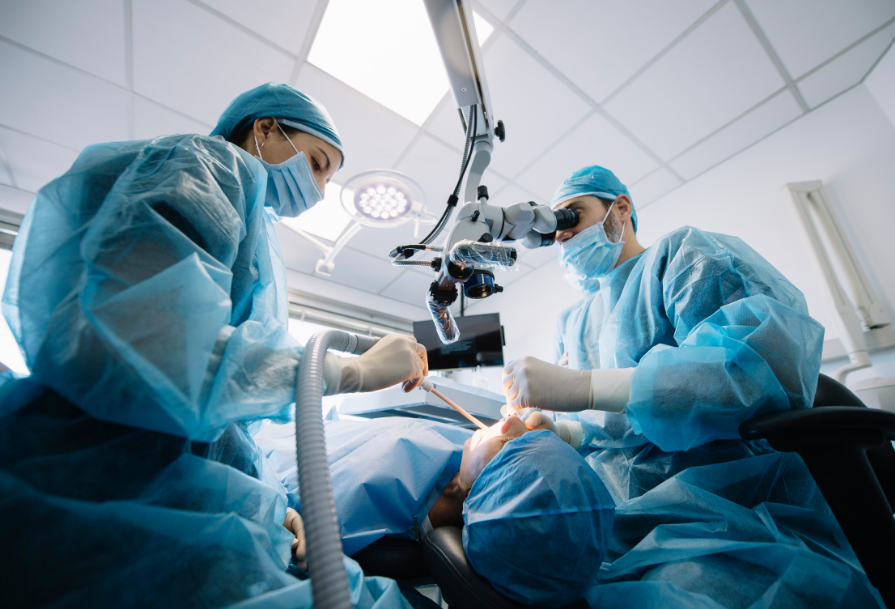 Patient undergoing dental surgery with two surgeons gathered around