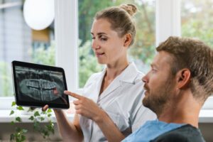 Hygienist showing patient X-ray of wisdom teeth.